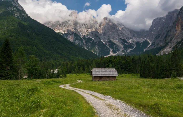 cottage in the krnica valley with julian alps mountains in the background scaled