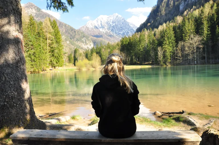 tyttö istuu plansarsko jezeron reunalla slovenian mittakaavassa