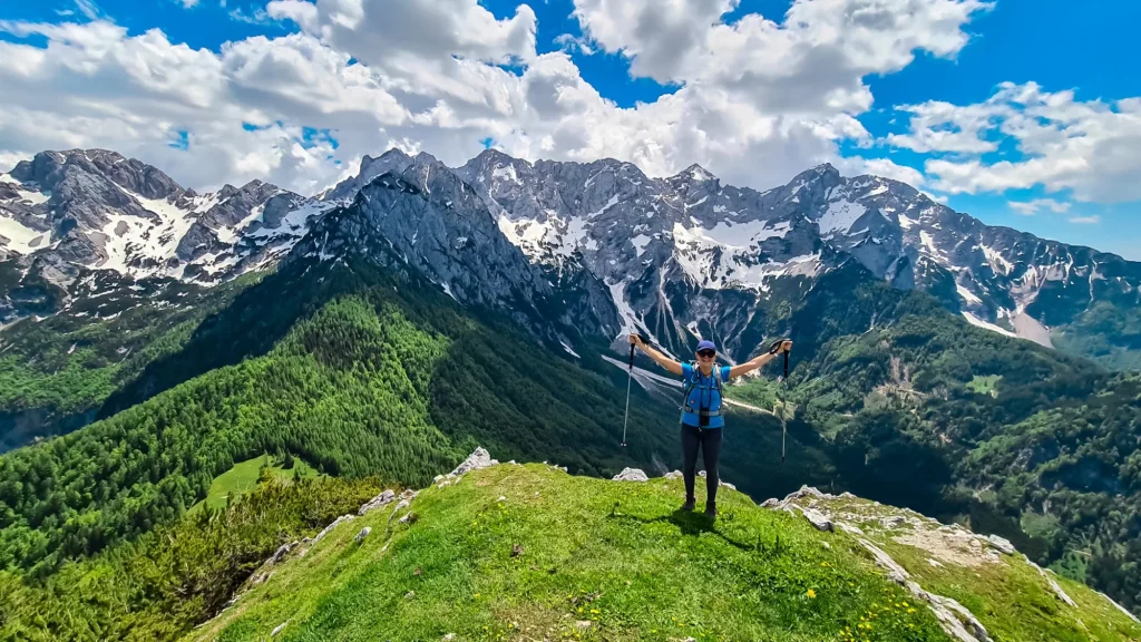 mujer feliz extendiendo los brazos de alegría en la cumbre de goli vrh con vista panorámica sobre las montañas kamnik savinja alpes escalada