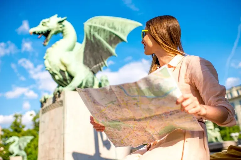 Girl holding a map next to Dragon Bridge in Ljubljana